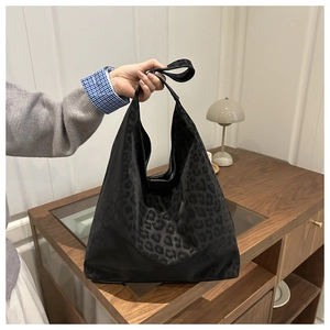 Détail de ce grand sac cabas hobo à motif léopard noir en toile avec bandoulière