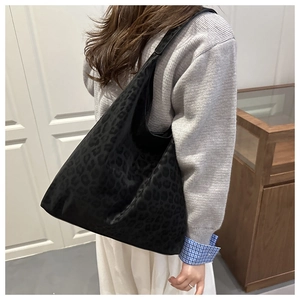Détail d'un grand sac cabas à motif léopard noir porté à l'épaule pour femme