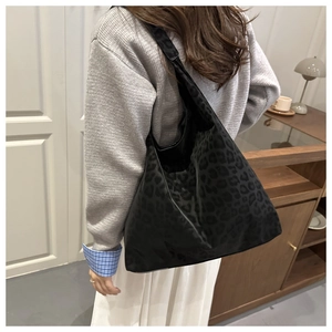 Detail of a large black leopard print tote bag worn on shoulder for winter fashion
