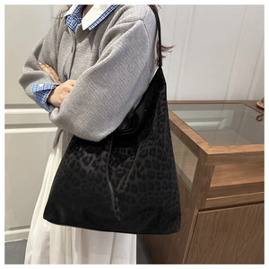 Grand sac cabas noir à imprimé léopard porté avec un cardigan gris décontracté