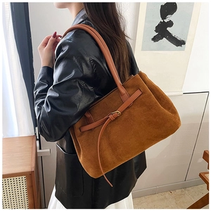 Detail of a brown suede tote bag with a leather buckle closure and shoulder strap