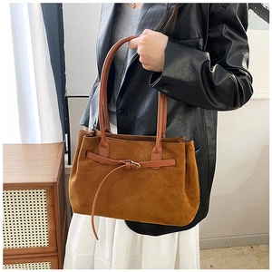 Detail of brown faux suede tote bag featuring slim straps and decorative metal buckle