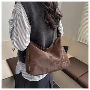 Detailed view of the textured brown suede crossbody bag with Tidal Dryness branding