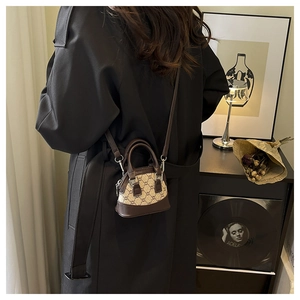 Chic retro monogram printed crossbody bag with leather trim worn by a model in black coat