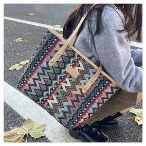 Detail of colorful zigzag woven tote bag featuring leather handles and gold rivet accents