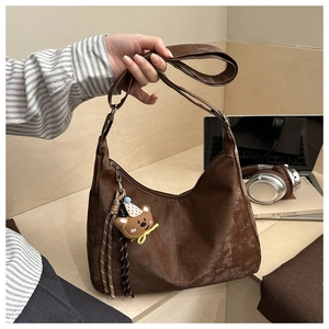 Detail of dark brown vintage hobo bag with adjustable strap and cute bear charm