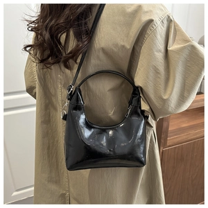 Dettaglio borsa in pelle nera lucida con fibbia in metallo argento su un trench coat