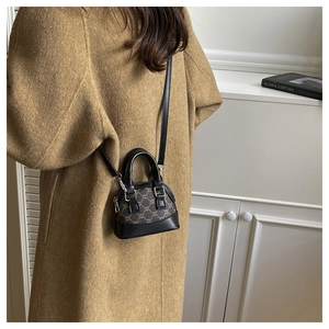 Detailed side view of mini shell bag with brown monogram pattern and black leather strap