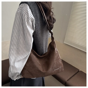 Detail of dark brown suede hobo bag featuring Tidal Dryness logo and soft matte texture