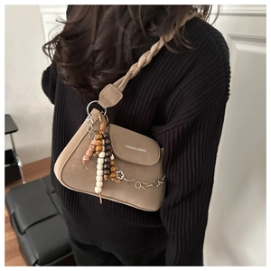 Brown frosted shoulder bag with braided strap and decorative bead charms shown on a model