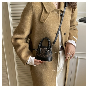 Detail view of mini monogram shell bag with black leather handles and long crossbody strap