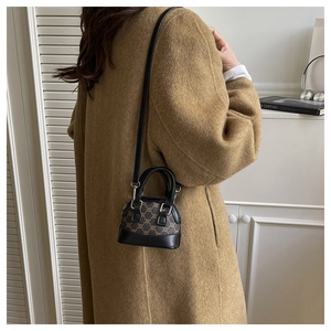 Sac bandoulière rétro en forme de coquille porté par un mannequin en toile monogrammée