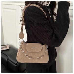 Detail of khaki suede textured handbag with woven strap and flower chain detail