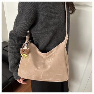 Détail du grand sac cabas beige vintage avec pendentif ours et logo gravé discret