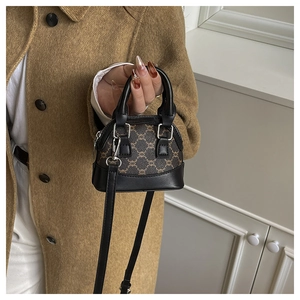 Detail of a mini shell bag in dark brown monogram pattern with black leather handles