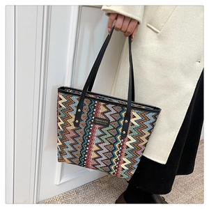 Detail der bunten Zickzack-Jacquard-Tasche mit schwarzem Ledergriff und Nieten