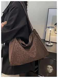 Close-up of a deep brown leopard print tote bag in soft suede texture with wide shoulder strap