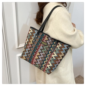 Detail of colorful woven tote bag featuring geometric wave patterns and leather handles