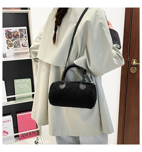 Close-up of black fuzzy lambskin cylinder bag featuring smooth leather handle and strap