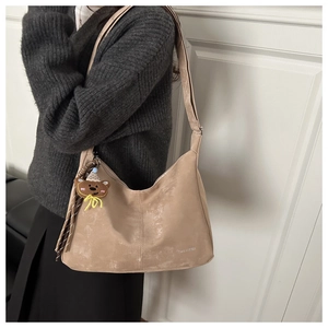 Detail of khaki suede shoulder bag with high-capacity design and a cute bear charm