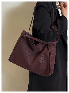 Model wearing a burgundy leopard print faux leather tote bag with a minimalist design
