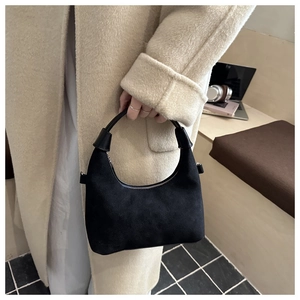 Dettaglio della borsa a mezzaluna in camoscio nero con manico in pelle liscia