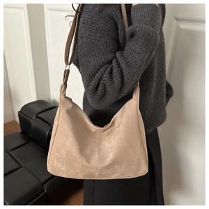 Detail of light beige suede Hobo bag with vertical stitching and metal brand lettering