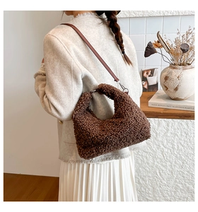 Dettaglio della texture in peluche marrone scuro della borsa a mezzaluna con tracolla