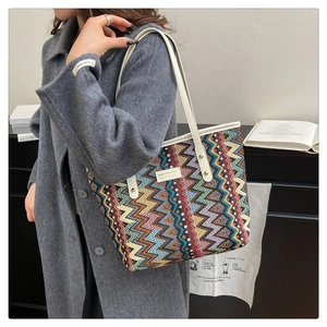 Close-up of a colorful zigzag knit tote bag with thick canvas handles and rivet details