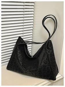 Détail du motif léopard noir mat sur un grand sac cabas porté épaule de haute capacité