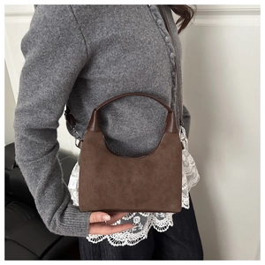 Dettaglio della borsa a mezzaluna in camoscio marrone scuro con finiture in pelle liscia