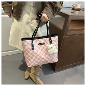 Dettaglio della borsa tote a quadri rosa con placca logo in metallo e ciondolo a orsetto