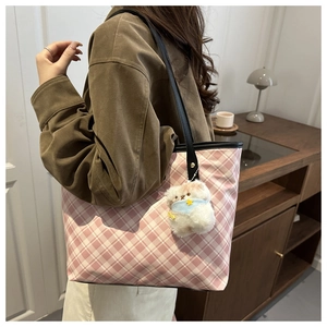 Vista dettagliata di una grande borsa tote a scacchi con ciondolo a orsetto su modella