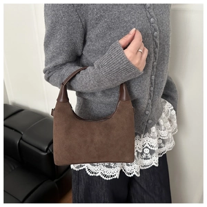 Borsa hobo in camoscio marrone con finiture in pelle liscia in un ambiente elegante