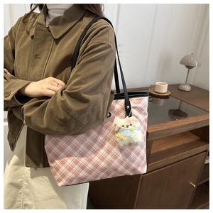 Borsa tote a scacchi rosa e bianca con ciondolo a forma di orso indossata da modella