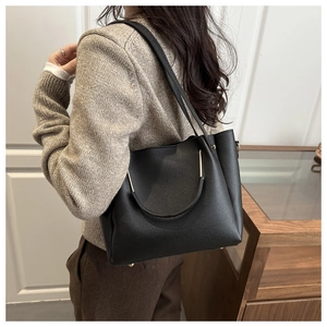 Dettaglio della borsa tote in pelle martellata nera con manici a U in metallo oro