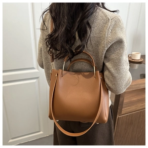 Borsa tote in pelle marrone con grana litchi e dettagli dorati mostrata in contesto casual