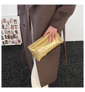 Detail of gold envelope clutch bag featuring sparkling rhinestones and rivet accents