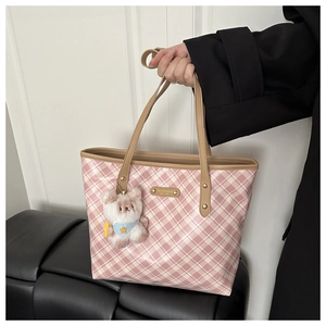 Dettaglio della borsa tote a quadri rosa con placca dorata e ciondolo a forma di orsetto