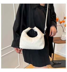 Dettaglio borsa hobo in pile bianco con tracolla in pelle su un cappotto nero