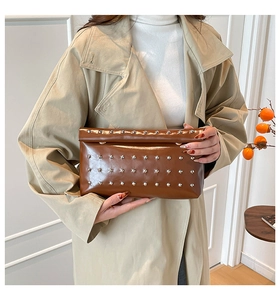 Close-up of caramel brown leather envelope clutch with silver stud rivets detailing
