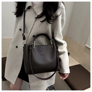 Dettaglio della borsa tote marrone scuro in pelle testurizzata su modella in cappotto
