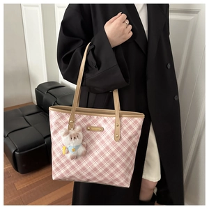 Dettaglio della borsa tote a quadri rosa con logo in metallo dorato e ciondolo a orsetto