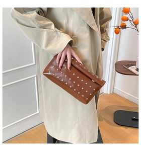 Gros plan de la pochette enveloppe marron avec rivets métalliques argentés et texture cuir chic