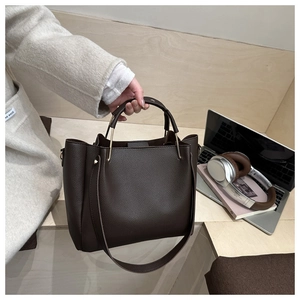 Dettaglio borsa tote marrone scuro in pelle martellata con manico ad anello dorato e tracolla
