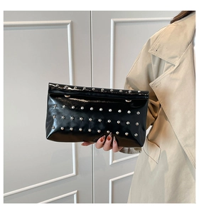 Close-up of black patent leather clutch with silver rivets and magnetic snap closure