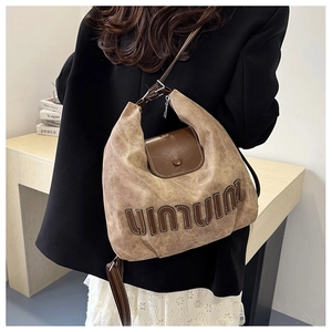 Detail of vintage brown canvas and leather backpack featuring elegant letter design