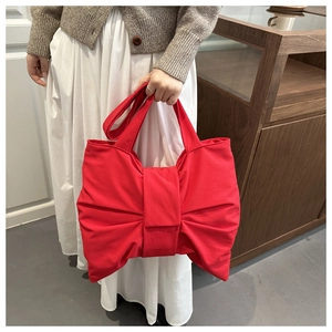 Dettaglio di una borsa tote in tela rossa con un grande fiocco decorativo applicato
