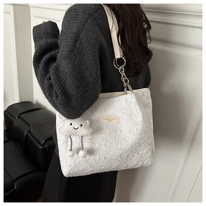 Dettaglio della borsa tote bianca con texture plissettata, catena e ciondolo a nuvola