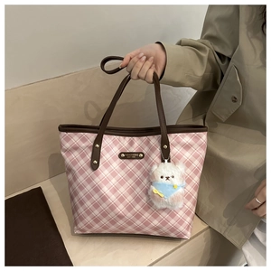 Dettaglio della borsa tote a scacchi rosa con manici in pelle e ciondolo a orsetto